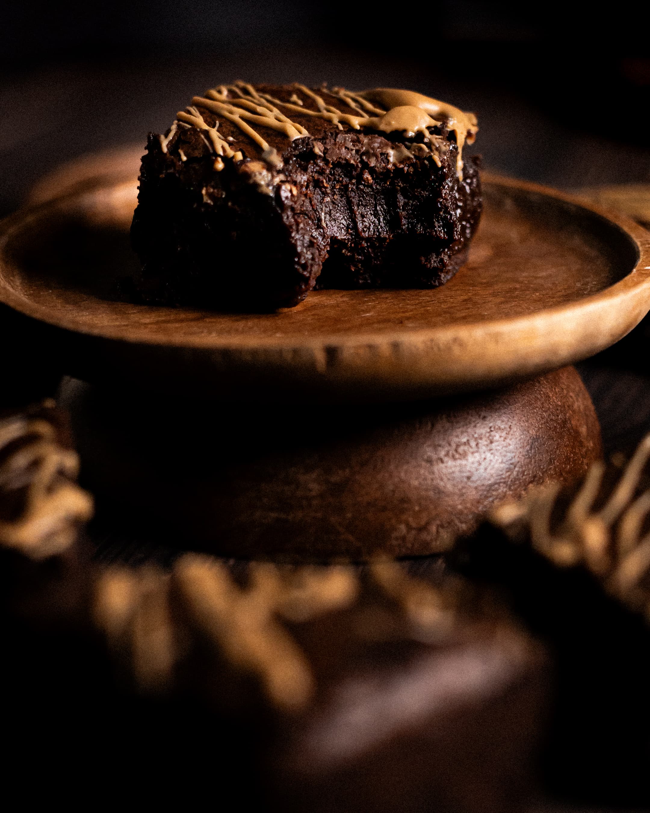 a single chai brownie with a bite taken out, showing teeth marks in its gooey centre, surrounded by more chai brownies 