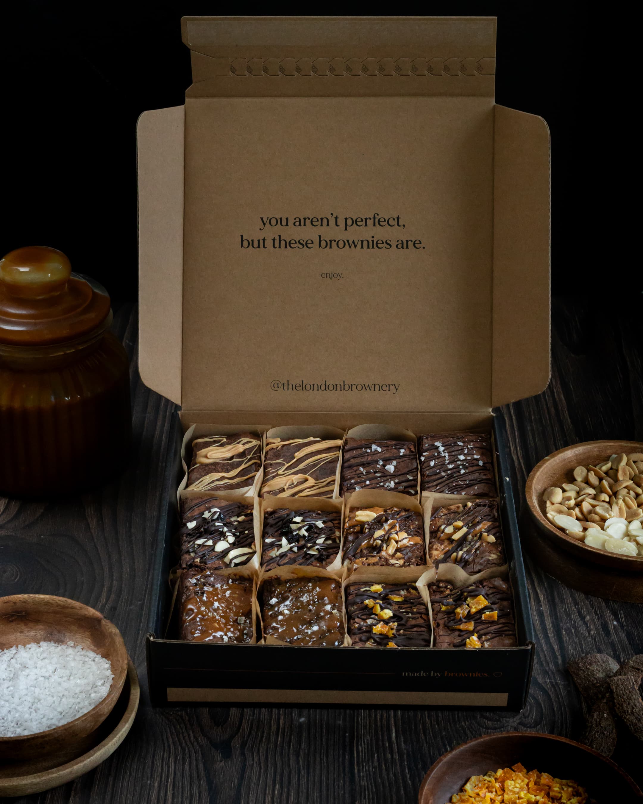 a box of six different flavours of brownies, surrounded by the ingredients that goes into them