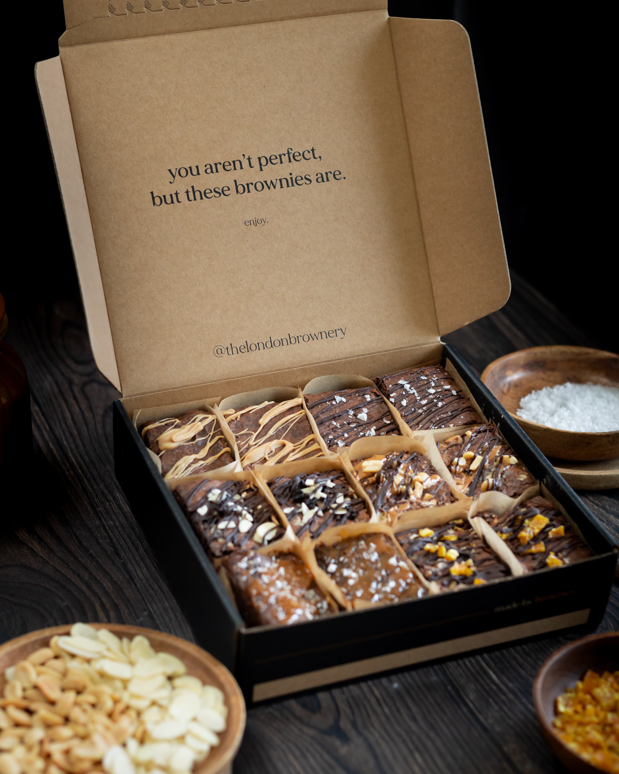 close up of a box of six different flavoured brownies with ingredients around 