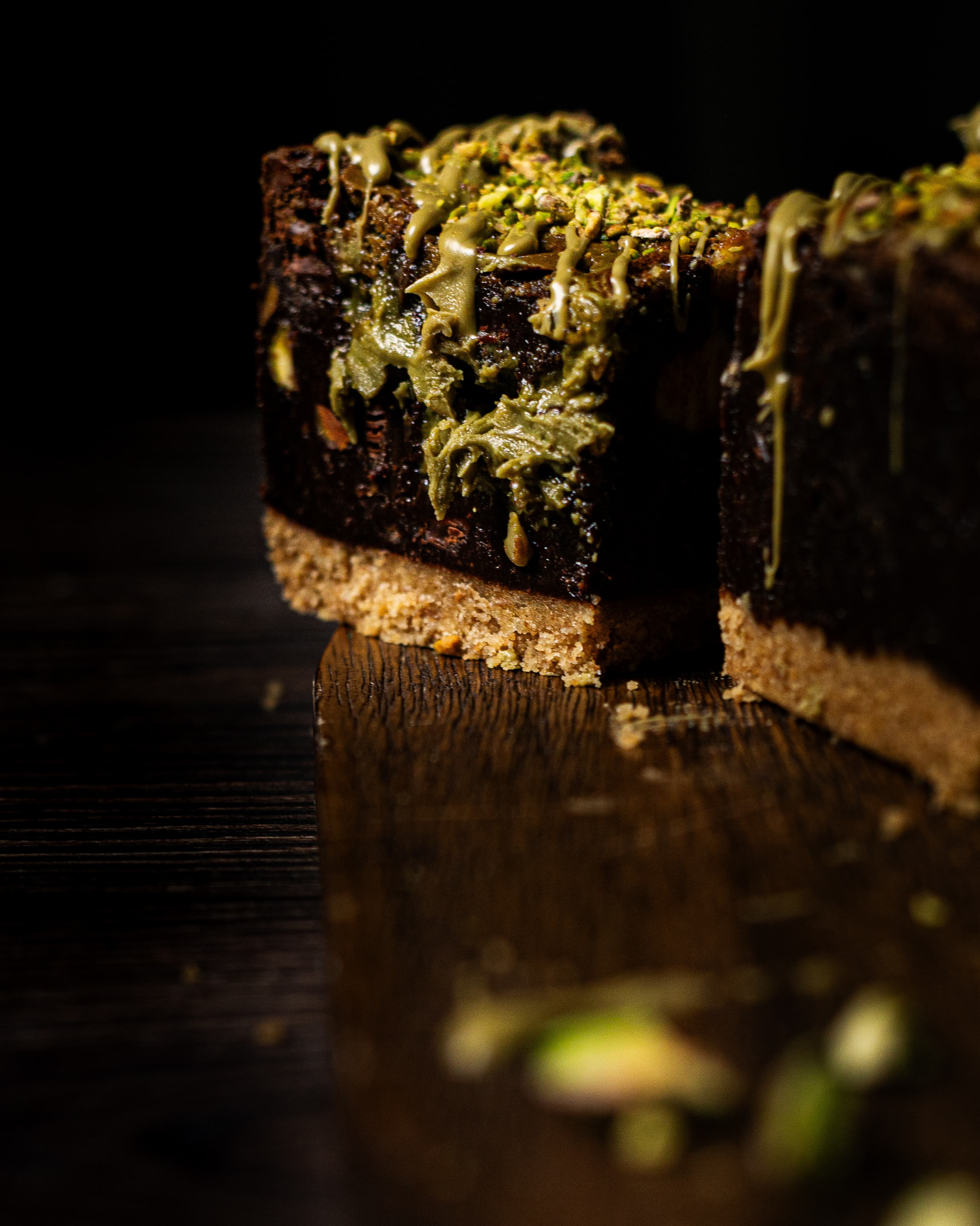 side profile of pistachio cheesecake brownie with pistachio cream oozing out