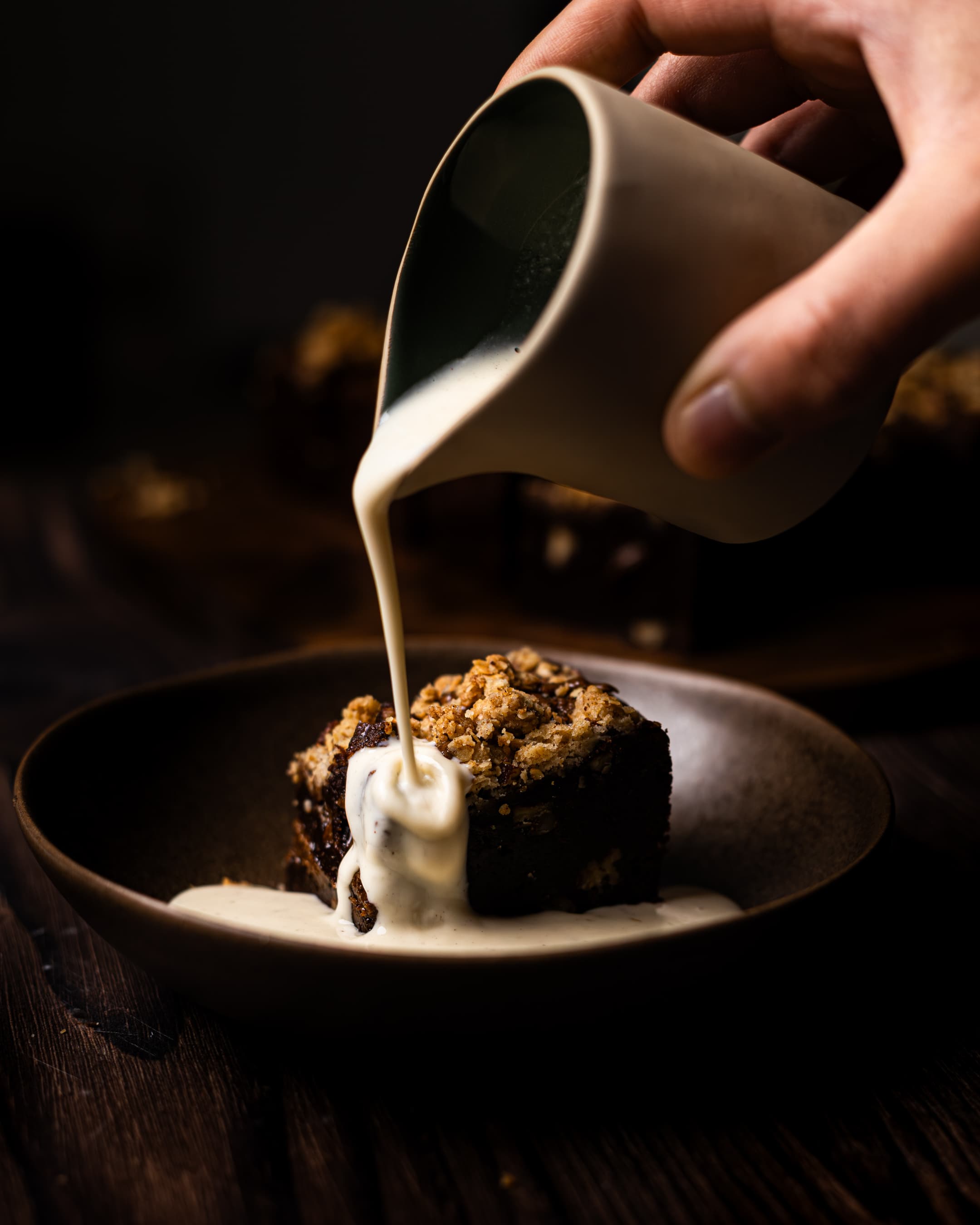 custard being poured on pecan crumble brownie